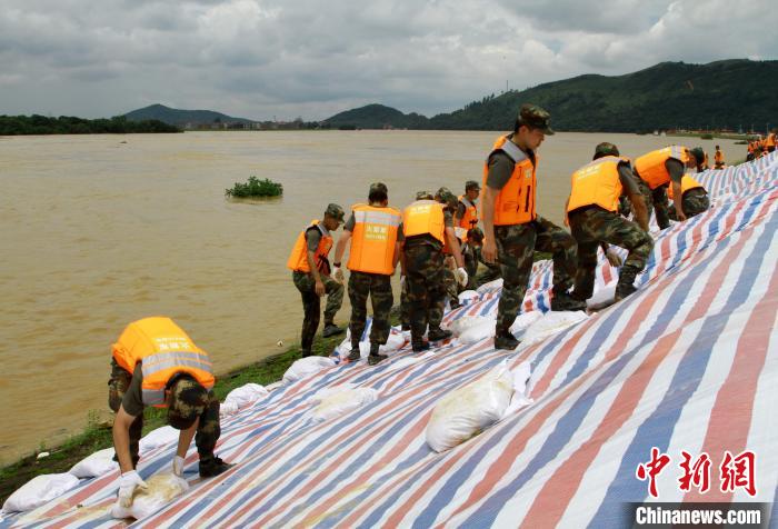 6月21日，驰援江西乐平的火箭军某部指战员正在乐北联圩紧急铺设防浪布，用沙袋加固河堤。　程万海 摄